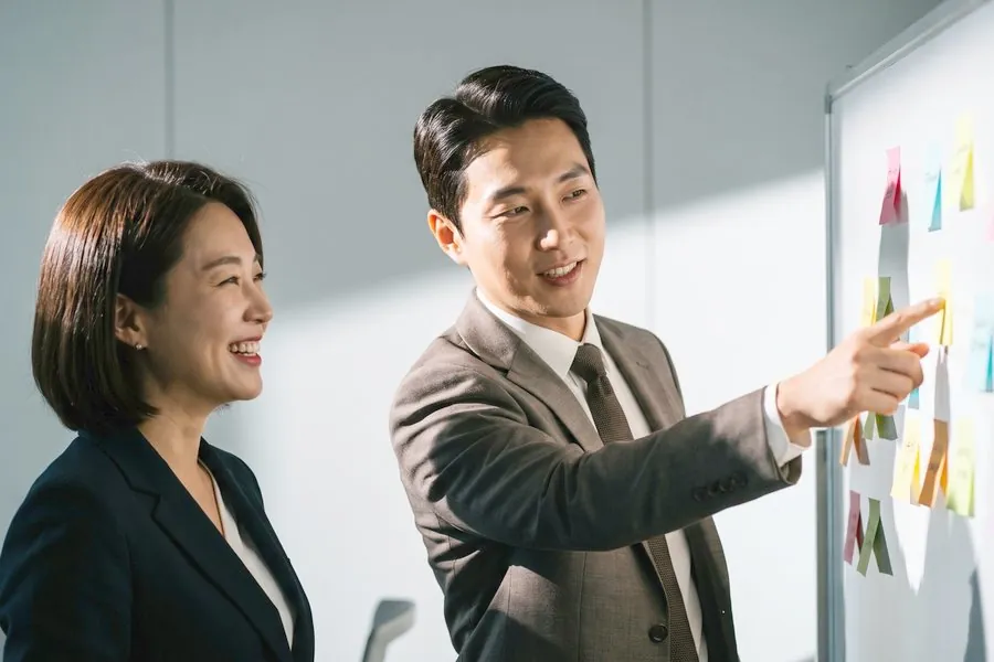 포스트잇이 붙은 화이트보드 앞에서 전략을 설명하는 컨설턴트